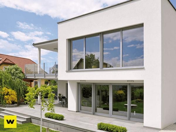 Modernes Einfamilienhaus mit großer Terrasse, bodentiefen Fenstern und Garten im Sommer.