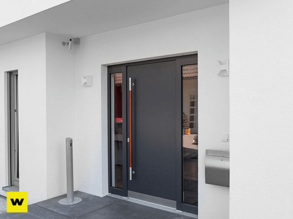 Moderne graue Haustür mit Glaseinsätzen an weißer Fassade und Briefkasten außen.